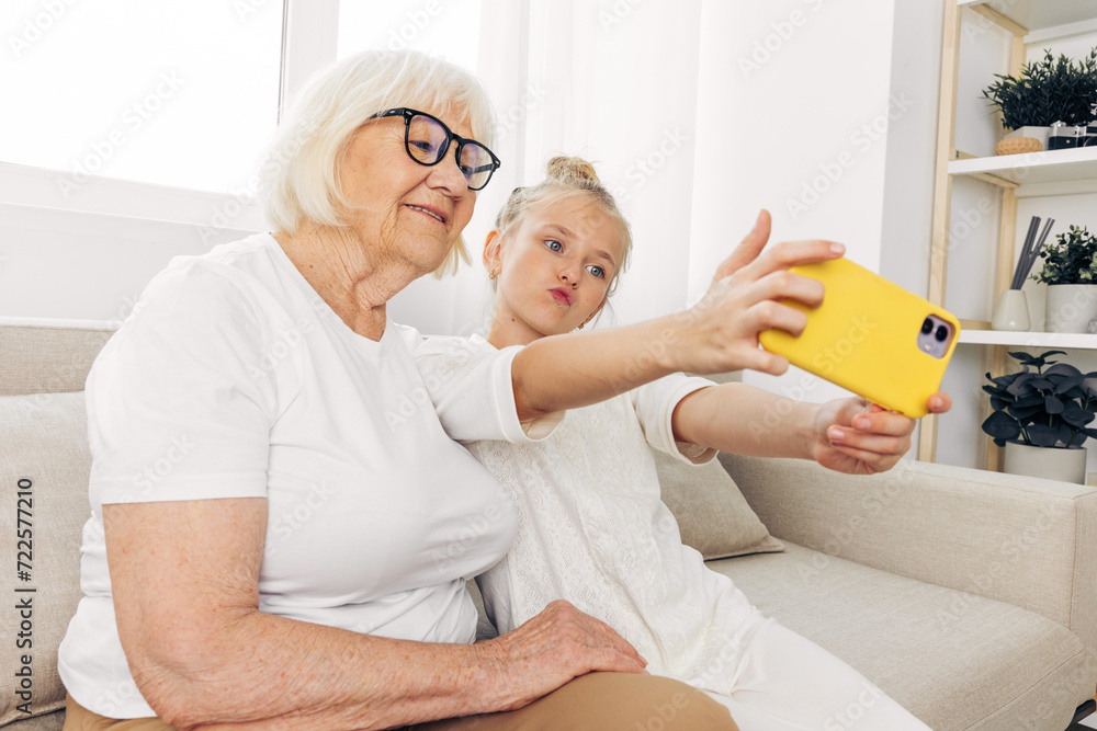© SHOTPRIME STUDIO - Family grandmother smiling phone hugging bonding selfie togetherness granddaughter child sofa © SHOTPRIME STUDIO - Family grandmother smiling phone hugging bonding selfie togetherness granddaughter child sofa