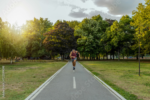 Unusual point of view. Sport, lifestyle concept, copy space. Sportsman jogging in the forest. Healthy lifestyle. Handsome male, jogging in the park, wearing headphones, listening music.