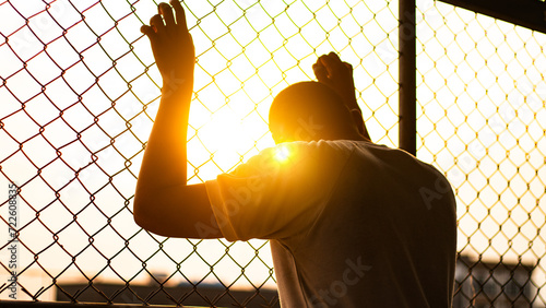 Silhouette of a man behind the fence, Silhouette photo of  feeling upset, sad, unhappy or disappoint crying. Young people mental health care problem lifestyle concept, frustrated standing hopelessly photo