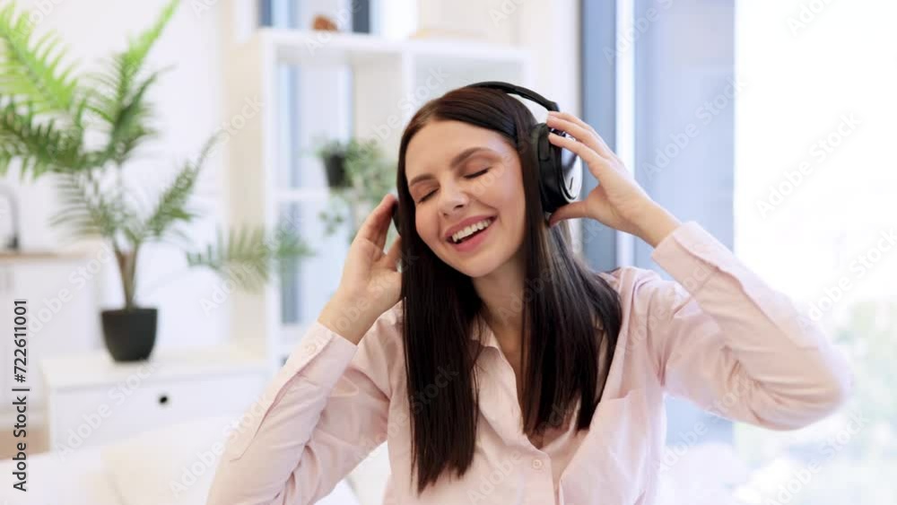 Happy lady in headphones sitting on comfy bed and enjoying relaxing music on weekend. Portrait of happy pretty woman using modern device listening favorite music at home. Happy lady in headphones sitting on comfy bed and enjoying relaxing music on weekend. Portrait of happy pretty woman using modern device listening favorite music at home.