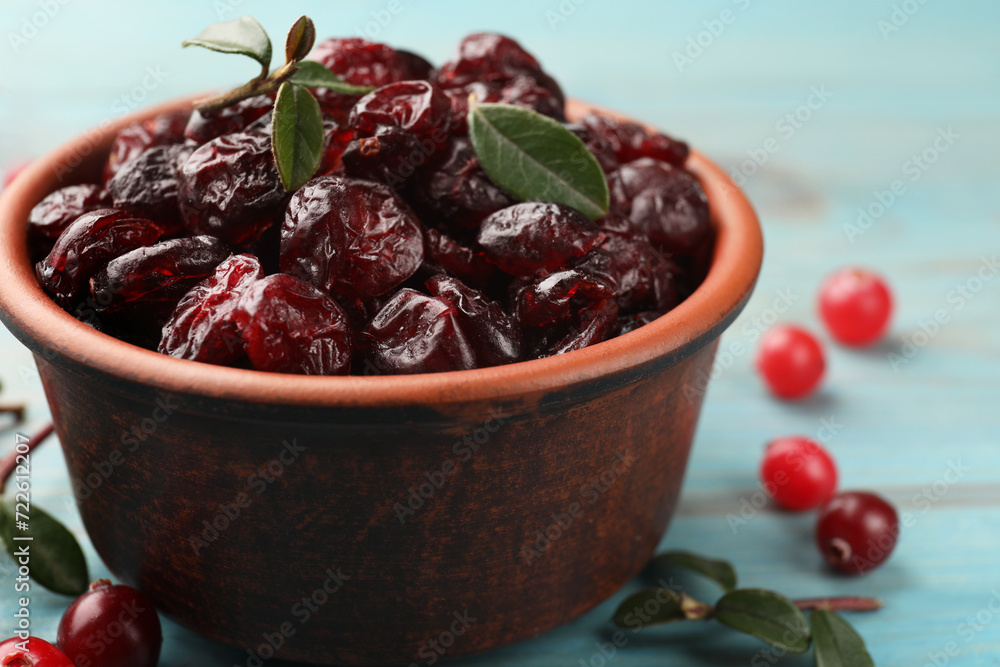 Tasty dried cranberries in bowl, fresh ones and leaves on table, closeup Tasty dried cranberries in bowl, fresh ones and leaves on table, closeup
