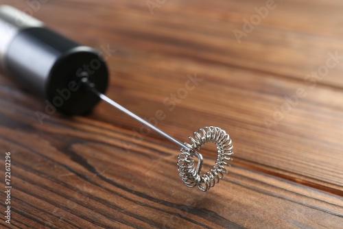 Black milk frother wand on wooden table, closeup. Space for text