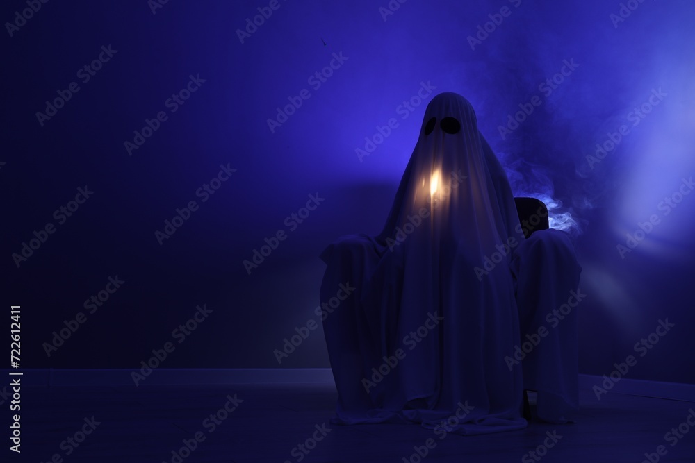 Creepy ghost. Woman covered with sheet sitting in armchair in blue light, space for text Creepy ghost. Woman covered with sheet sitting in armchair in blue light, space for text