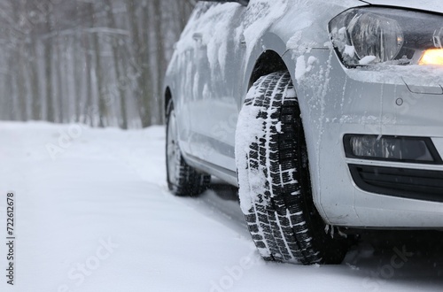 Car with winter tires on snowy road in forest, space for text