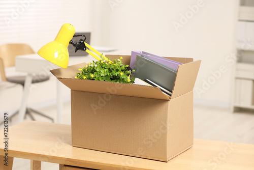 Unemployment problem. Box with worker's personal belongings on desk in office
