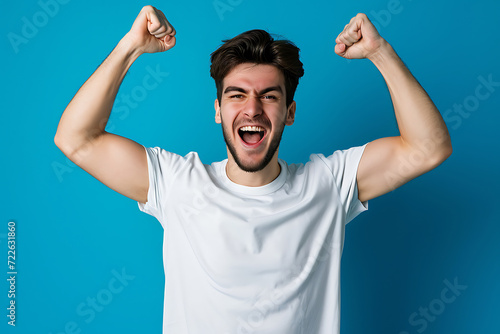 Photo of ecstatic young man shout loud yeah fist up raise win lottery isolated blue background