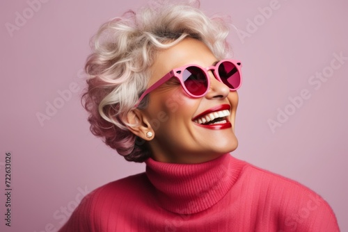 Portrait of a beautiful smiling woman in pink sweater and sunglasses.