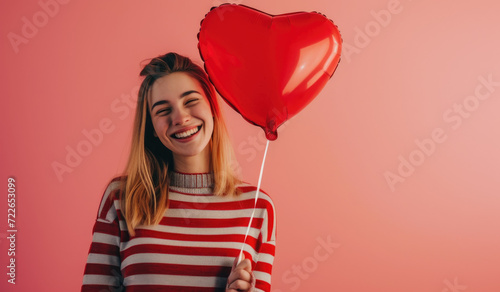 a smiling beautiful girl holding pink balloon against pink background © Kien
