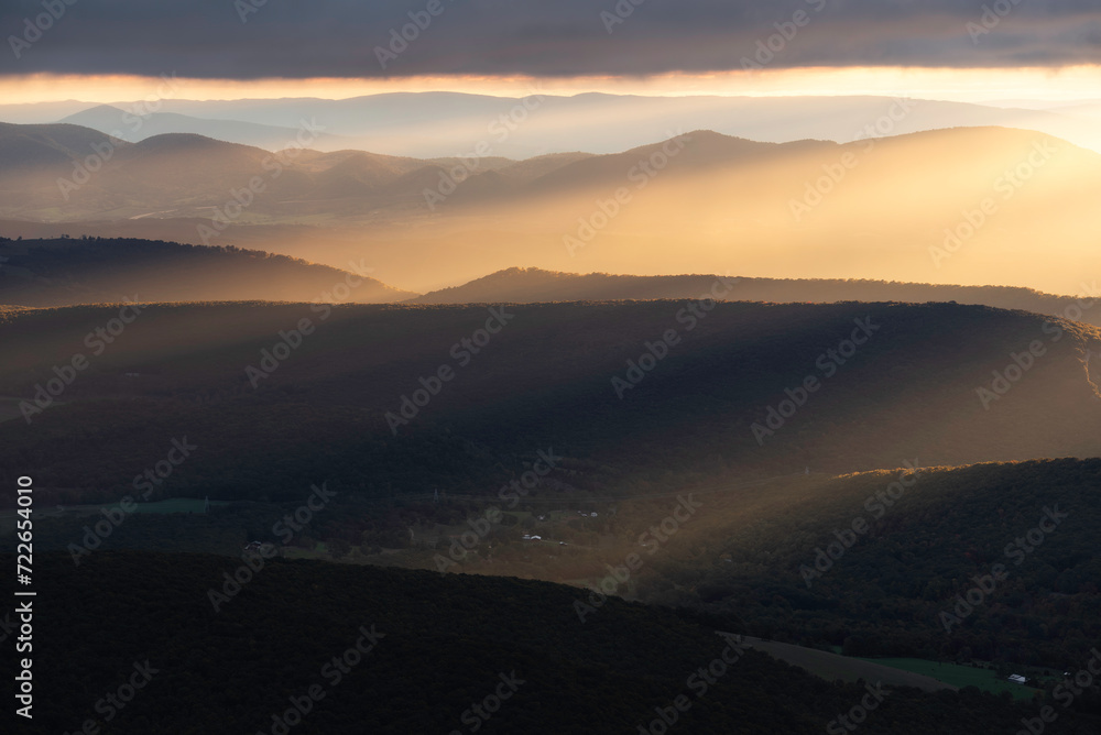 Intense sunlight fill the valleys of West Virginia during an overcast Autumn sunrise in the Appalachian Mountains.