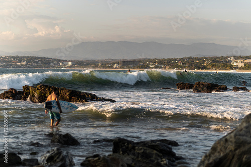 Surfers waiting waves at sunset in Pacific Coast of Oaxaca, Mexico photo