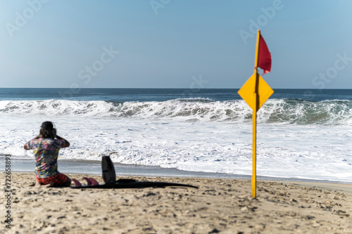 Lone surfer sit on sandy beach watching the crashing ocean waves in Zicatela beach, Oaxaca, Mexico photo