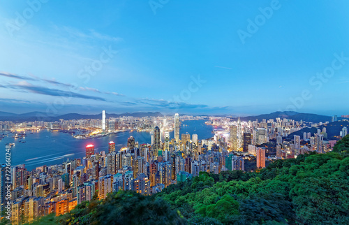 Romantic scene of Hong Kong at nightfall, with residential towers on Mid-Levels hillside in Hong Kong Island  colorful city lights of skyscrapers by Victoria Harbour dazzling under moody twilight sky