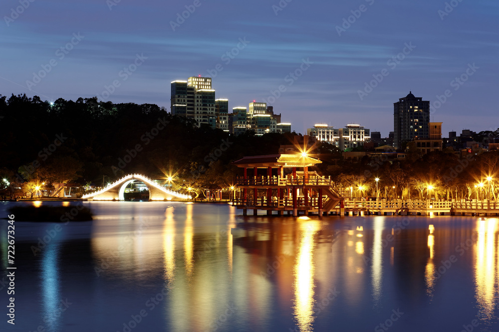 A beautiful corner of Dahu Community Park with a traditional arch bridge and an oriental pavilion by lakeside in Taipei City, Taiwan ~ Night scene of an urban park with lights reflecting on lake water