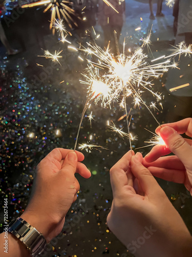 Three hands are holding sparkler. At the New Year's party.