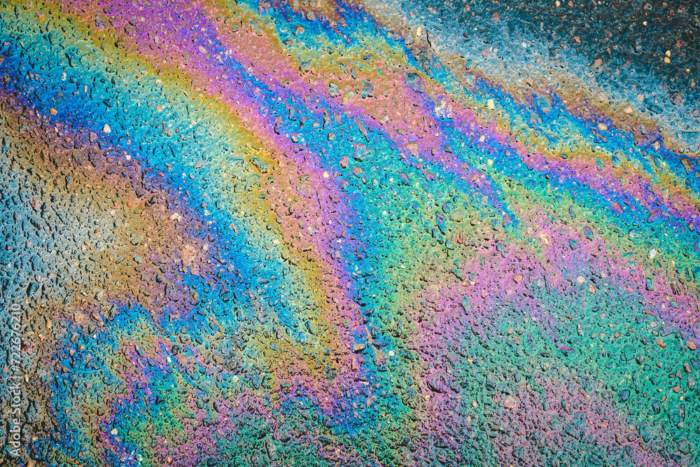 Rainbow gasoline oil spill on the pavement as a texture or background.