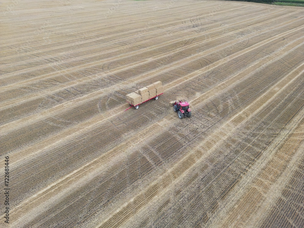 Tracteur chargeant une remorque avec une botte de paille