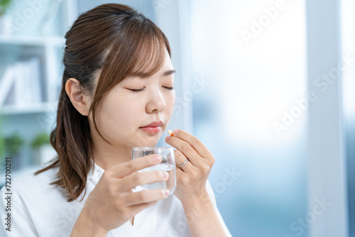 自宅で薬を飲む日本人女性