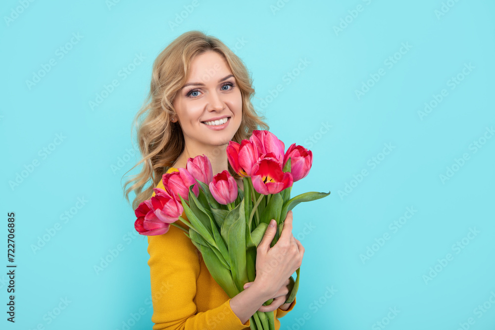 happy young woman with tulip flowers on blue background