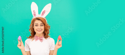 surprised redhead woman in bunny rabbit ears with painted eggs, happy easter. Woman isolated face portrait, banner with mock up copyspace. photo