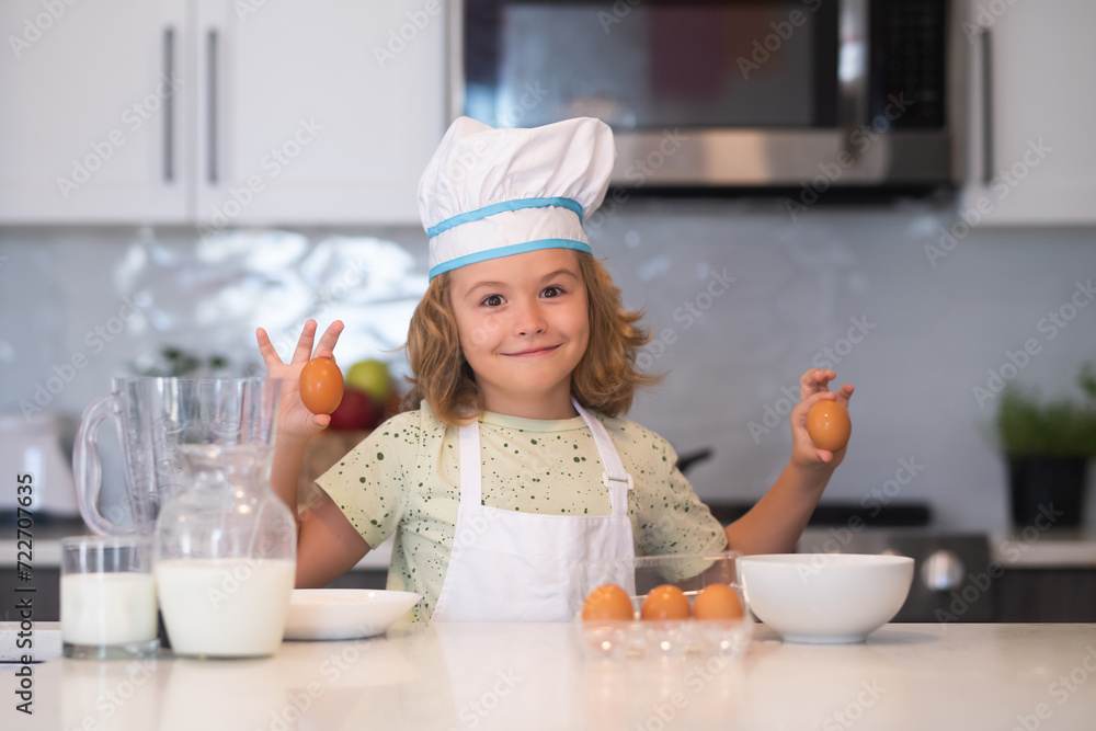 Funny kid with eggs at kitchen. Chef kid cook baking at home kitchen. Kid chef cook cookery at kitchen. Cooking, culinary and kids. Little boy in chefs hat and apron. Funny kid with eggs at kitchen. Chef kid cook baking at home kitchen. Kid chef cook cookery at kitchen. Cooking, culinary and kids. Little boy in chefs hat and apron.