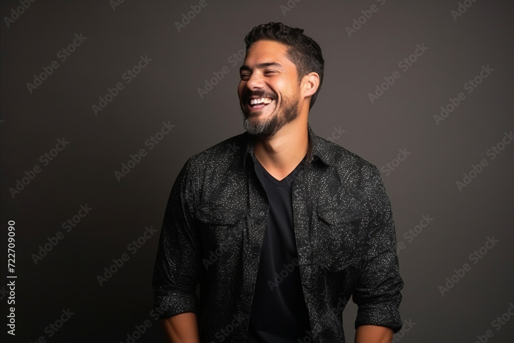 Handsome young man laughing and looking at the camera on a dark background Handsome young man laughing and looking at the camera on a dark background