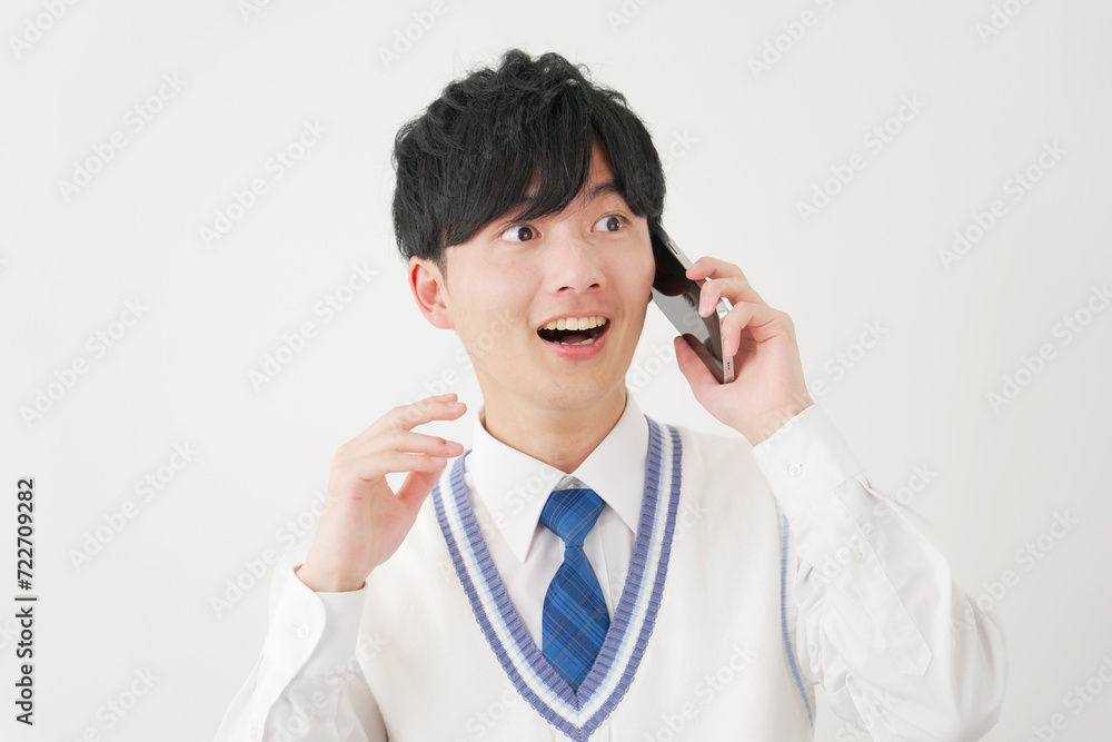 スマートフォンで電話しながら驚く男子高校生 白背景 スマートフォンで電話しながら驚く男子高校生 白背景