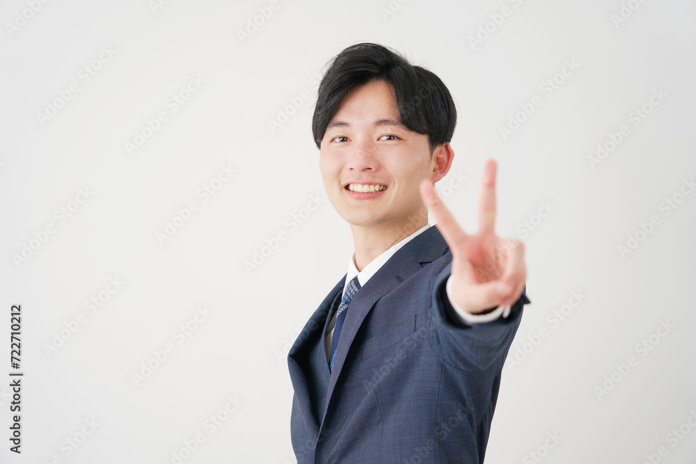 ピースサインをする若いビジネスマン　白背景