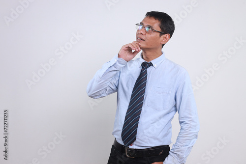 Pensive adult businessman in formal clothes touching chin and looking up thinking of something