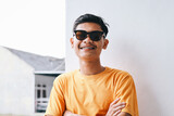 Stylish young guy hipster wear braces teeth and sunglasses standing in crossed arm with happy expression