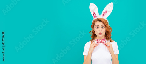Easter bunny woman. amazed happy easter girl in bunny ears and bow tie on blue background. Woman isolated face portrait, banner with mock up copyspace. photo