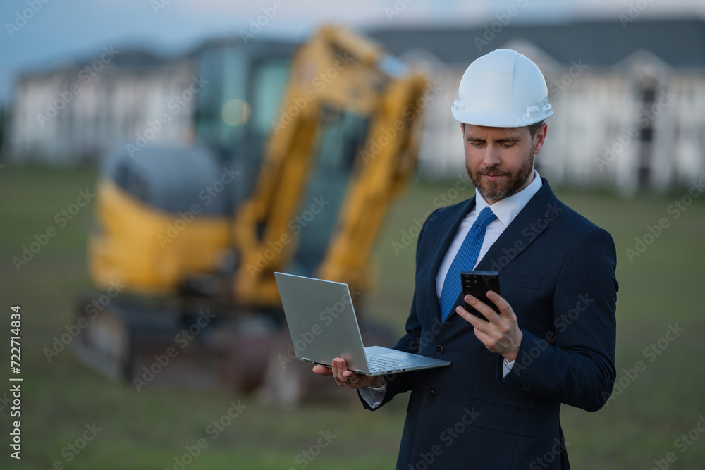 Civil engineer worker at a construction site. Engineer man in front of house background. Confident engineer worker at modern home building construction. Hispanic civil engineer in helmet.