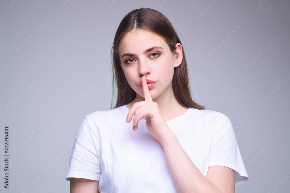 Beauty and silence concept. Portrait of attractive funny young lady showing shhh taboo sign with finger to lips over studio background, isolated. Shhh sign, facial expression, secret. Beauty and silence concept. Portrait of attractive funny young lady showing shhh taboo sign with finger to lips over studio background, isolated. Shhh sign, facial expression, secret.