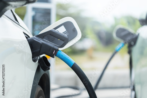 Concepts about using electric cars. Close up an electric car user is holding a black charger to recharge an electric car. The use of electric cars as the latest alternative energy source in Thailand. © SKT Studio