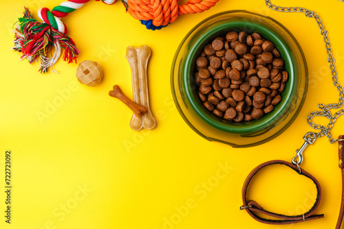 Dog food bowl and leash on yellow background
