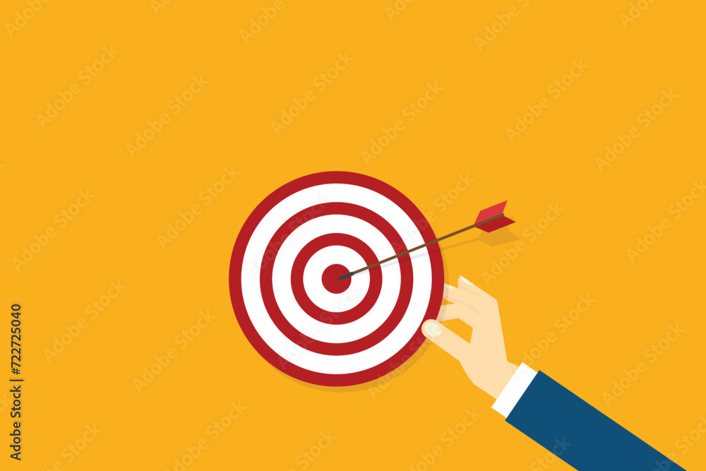 Hand holding a target, showing a goal. Red arrow hits the center. Business challenge failure and success concept. Hand holding a target, showing a goal. Red arrow hits the center. Business challenge failure and success concept.