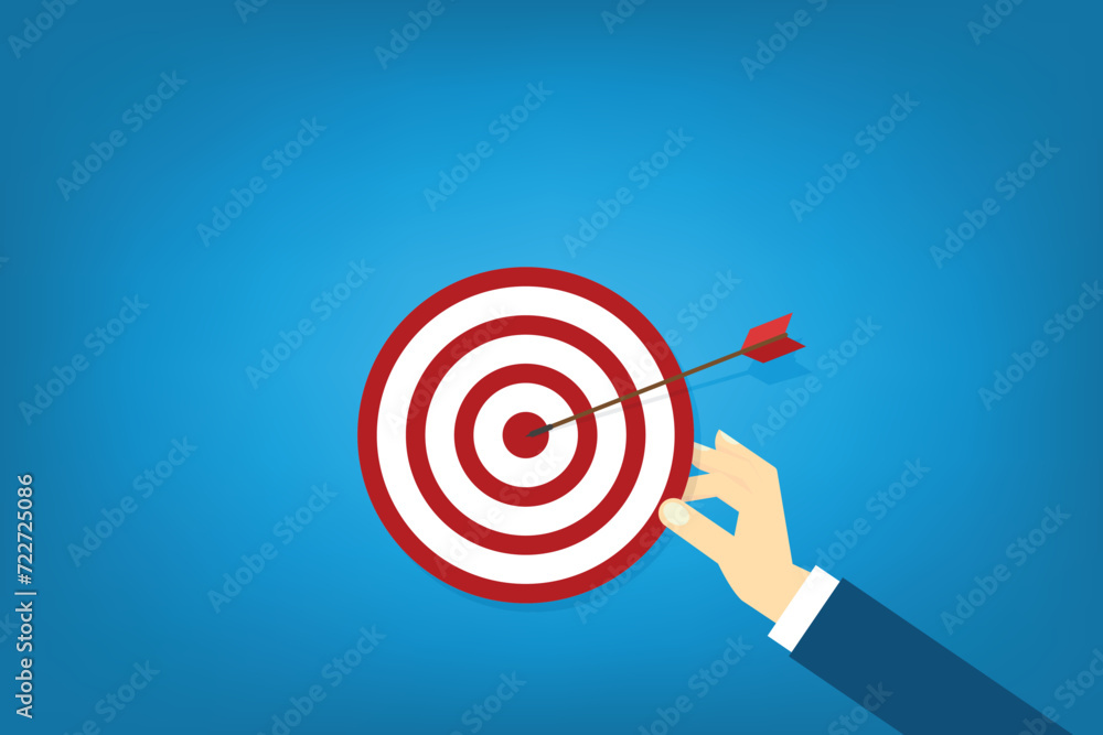 Hand holding a target, showing a goal. Red arrow hits the center. Business challenge failure and success concept. Hand holding a target, showing a goal. Red arrow hits the center. Business challenge failure and success concept.