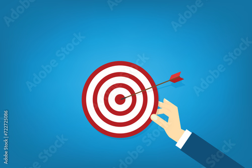Hand holding a target, showing a goal. Red arrow hits the center. Business challenge failure and success concept.	