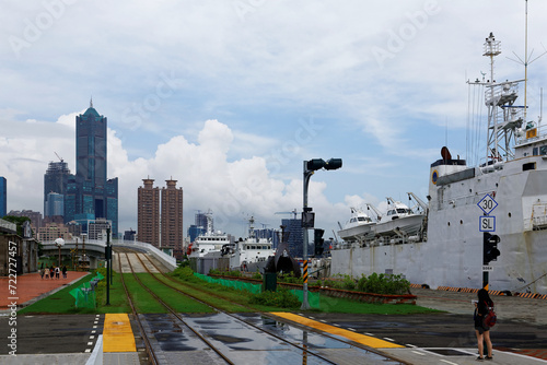 View of the tracks of the light rail metro system along the promenade of Pier-2 Art Center with 85 Sky Tower in background & ships of coast guard parking by the quayside of Kaohsiung Harbor in Taiwan  photo