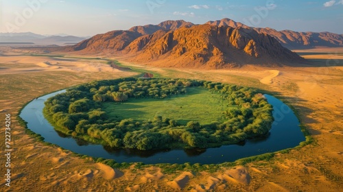  an aerial view of a circular shaped area in the middle of a desert with mountains in the background and a body of water in the middle of water in the foreground.