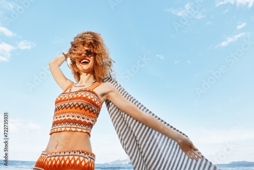 Sun-kissed Embrace: A Joyful Young Woman Enjoying Carefree Vacation on the Beach, Surrounded by Sunlight, Sea, and Blue Sky.