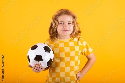 Child boy hold classic soccer ball isolated on yellow studio. Kid holding football ball in studio. Kid playing with ball. Sport, soccer hobby for kids. Little football player posing with soccer ball.