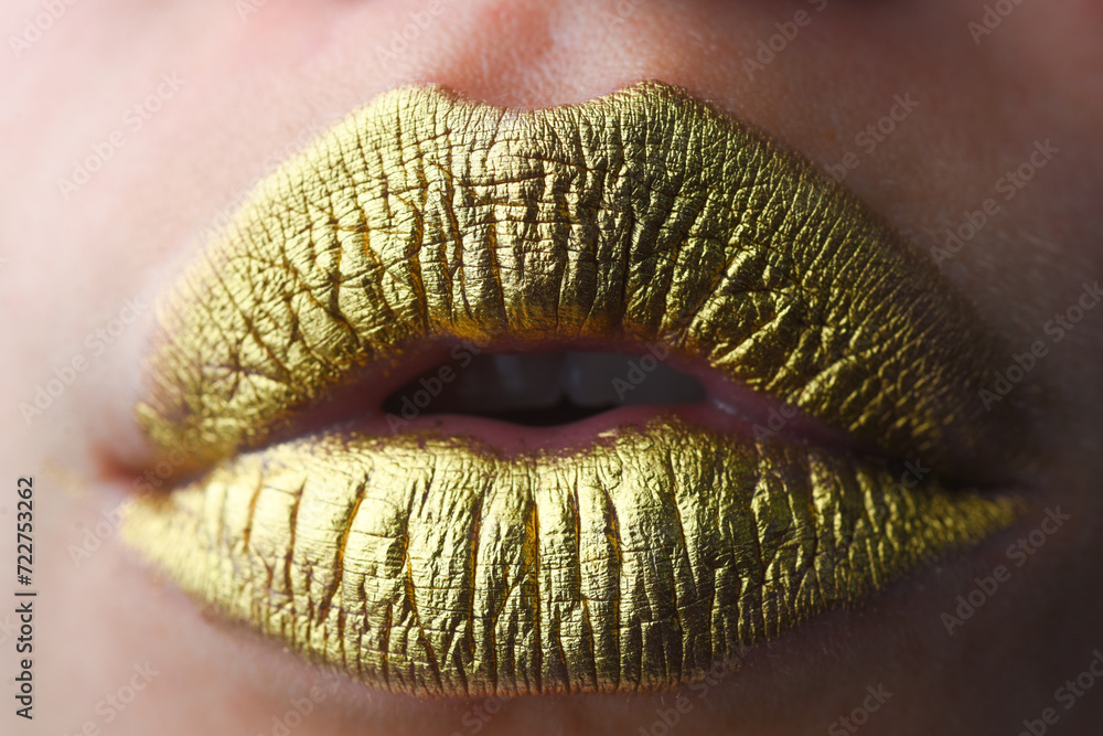 Fototapeta premium Gold lips. Gold paint on mouth. Golden lips. Luxury gold lips make-up. Golden lips with creative metallic lipstick. Gold metal lip. Sensual woman mouth, clse up, macro.