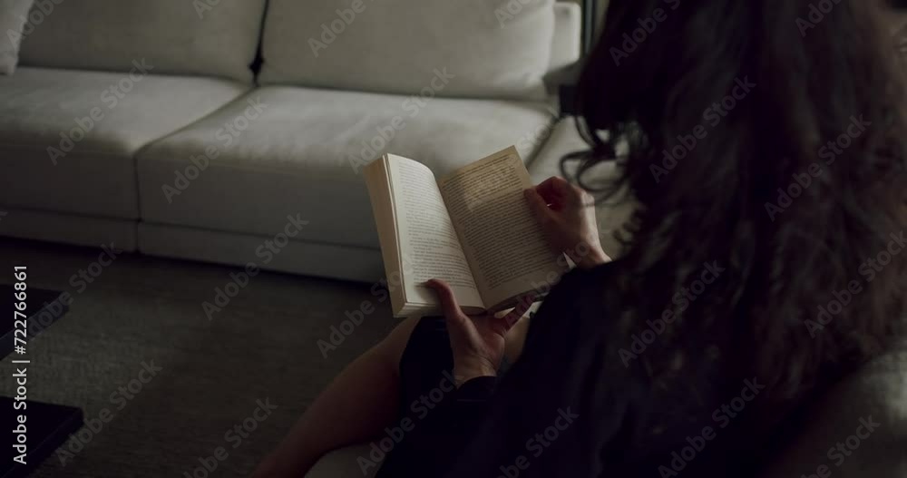Young woman reads favorite book sitting on floor near sofa in living room in flat. Young woman turns page of novel book to move forward in romantic story. Peaceful pastime at home Young woman reads favorite book sitting on floor near sofa in living room in flat. Young woman turns page of novel book to move forward in romantic story. Peaceful pastime at home