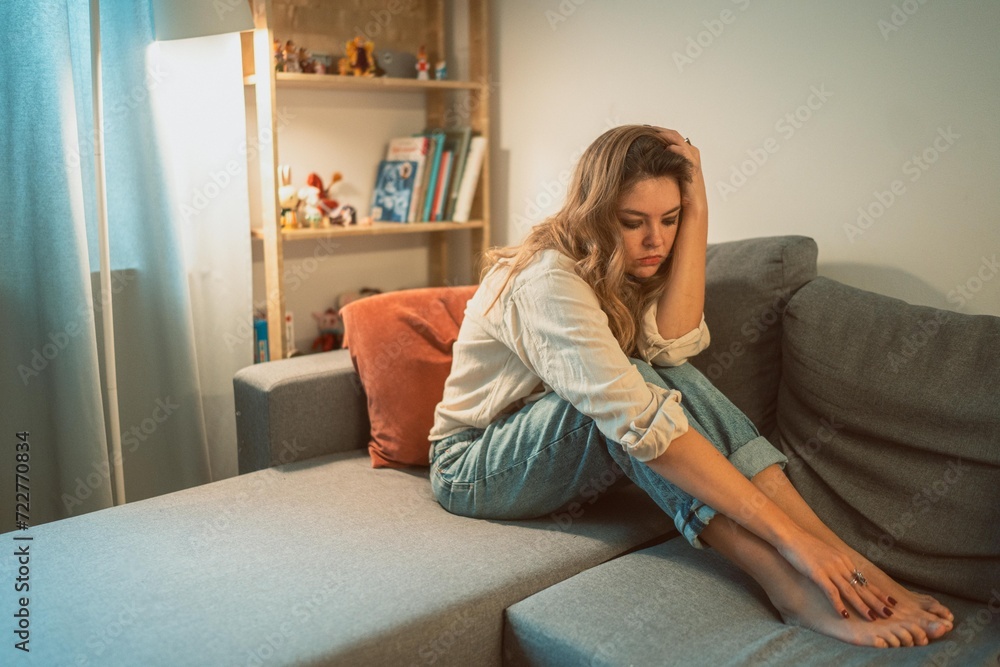 Obraz premium Young woman daydreaming while sitting on the sofa