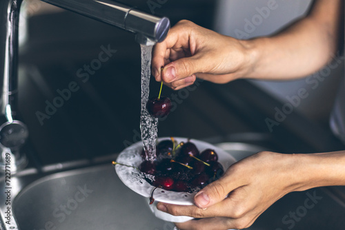 фотографія Midsection of human hands washing fresh sweet cherry