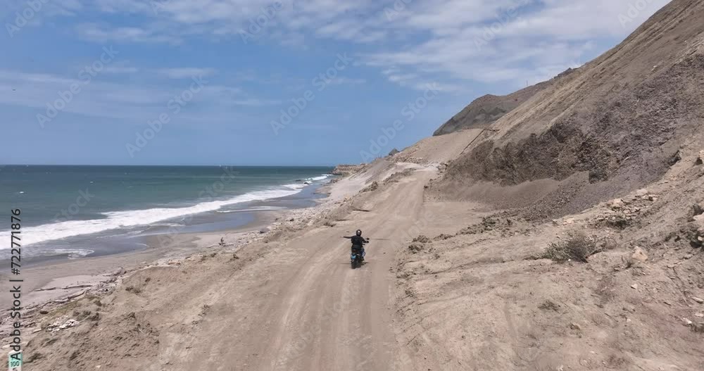 Aerial view of adventure motorcyclist on the road next to the beach Aerial view of adventure motorcyclist on the road next to the beach