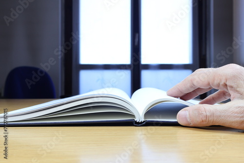 Diario aperto con pagina vuota sul tavolo, mano dell'uomo nel taccuino. photo