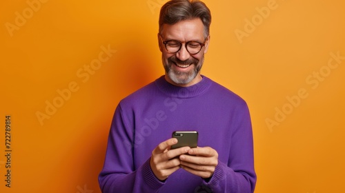  man in glasses and sweater using a smartphone on an orange background