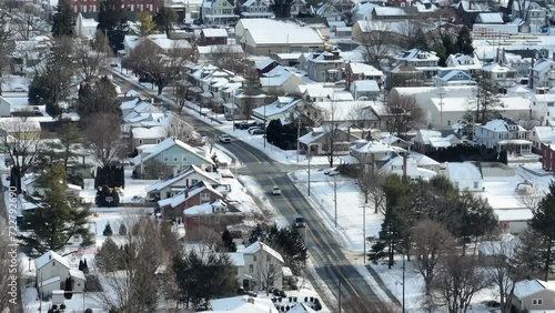 Christmas snow during holiday season in USA. Small town America after fresh winter snowfall. Cars pass by colorful homes lining street. Aerial drone view. photo