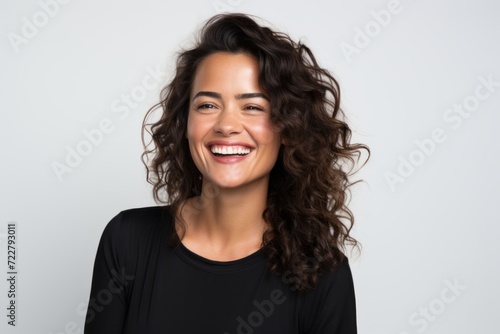Portrait of a smiling young woman with long curly hair on grey background